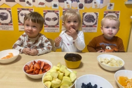 Trójka dzieci jedzą czekoladę i owoce